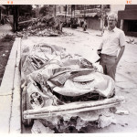 El Paso Times reporter David M Hancock stands next to flattened car in Mexico City, 1985