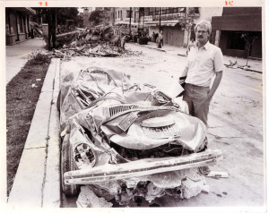 El Paso Times reporter David M Hancock stands next to flattened car in Mexico City, 1985